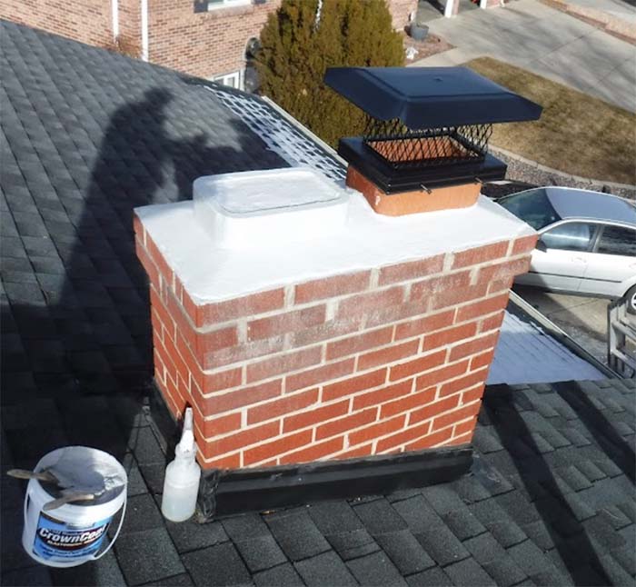 Red brick chimney with a black metal chimney cap
