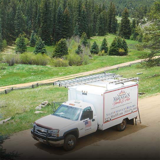 Work truck parked on dirt road with mountain and forest behind